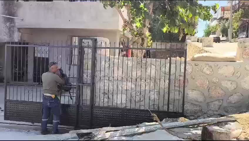 Bahçe girişindeki siyah metal kapı üzerinde çalışma