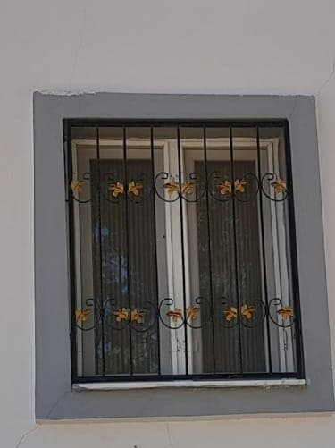 Pencere önündeki altın detaylı siyah güvenlik parmaklığı