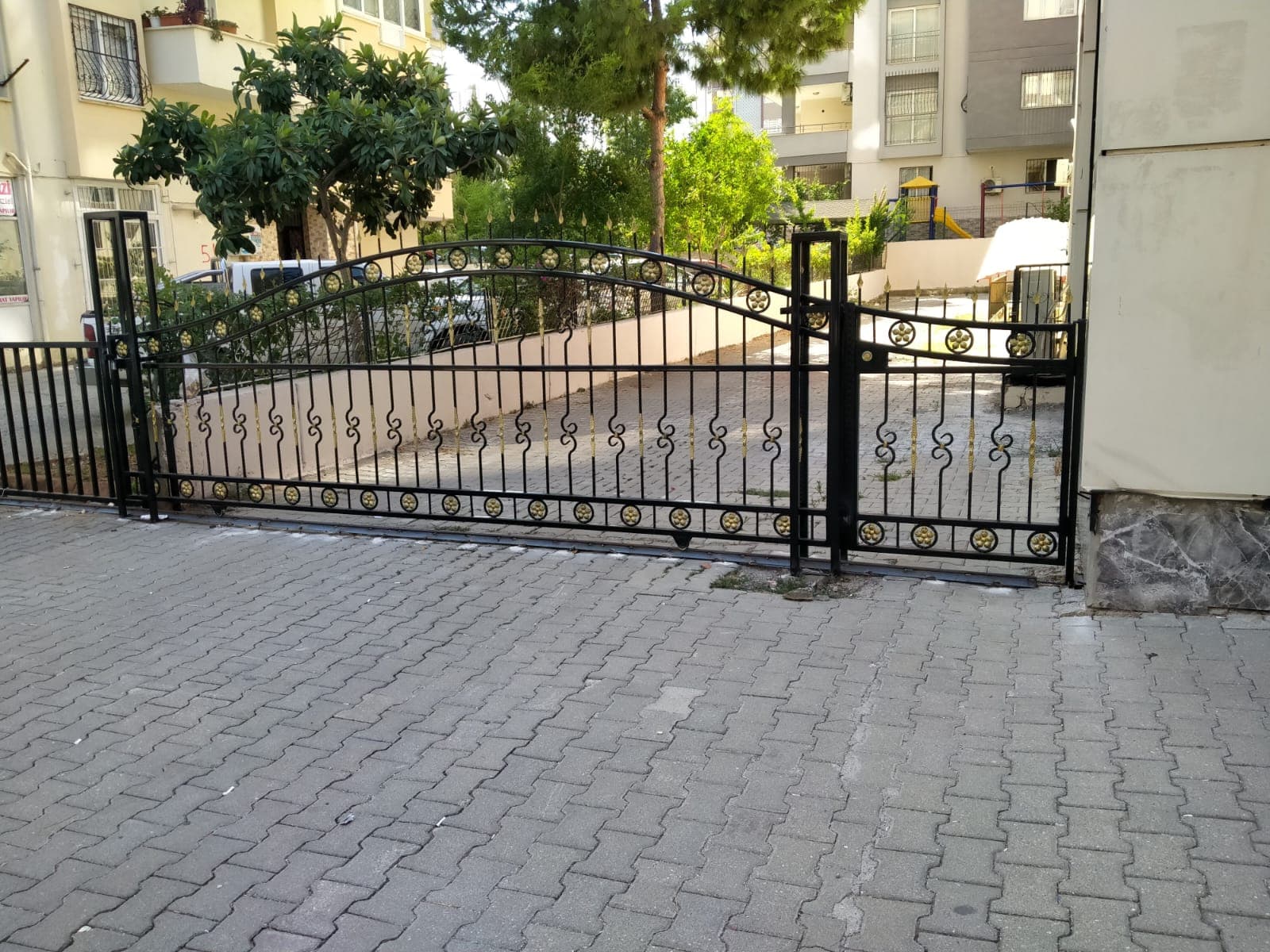 Bahçe girişinde açık çift kanatlı ferforje kapı