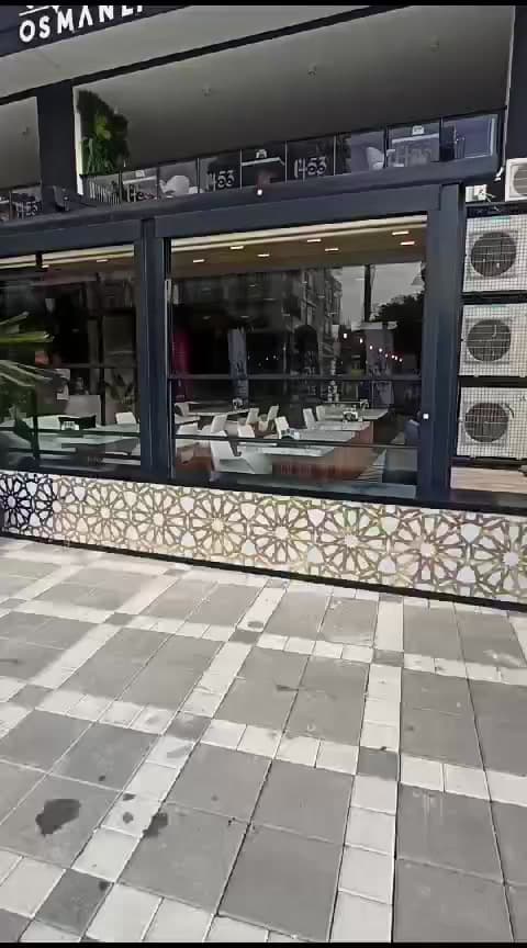 Desenli alt duvar üzerinde yükselen kafe cam cephesi
