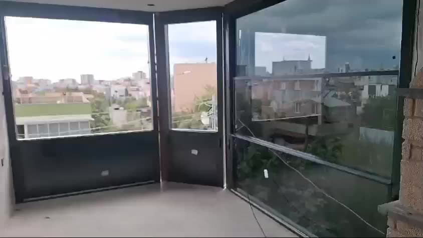 Terasın köşesini çevreleyen koyu profilli cam paneller