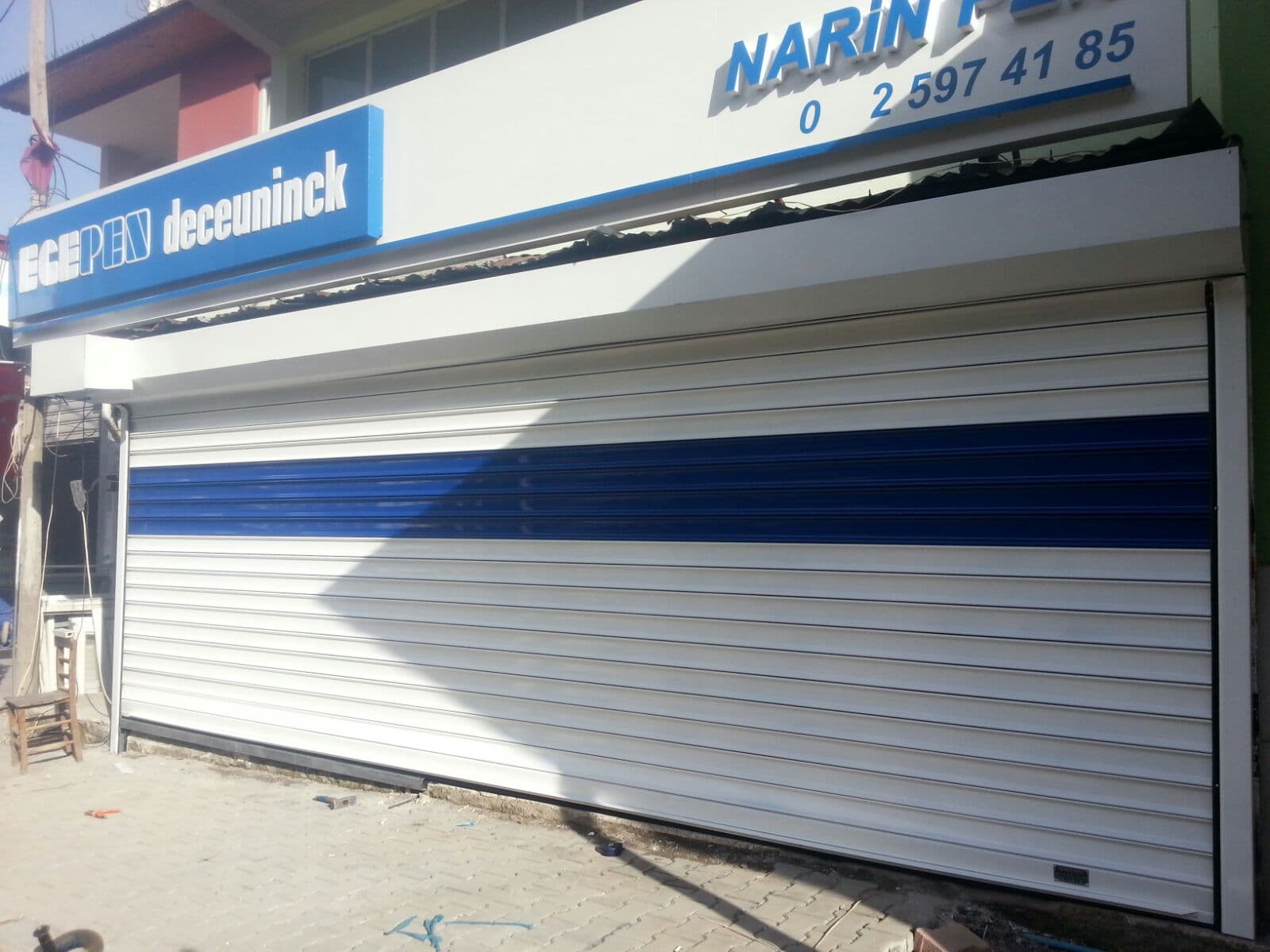 Teknik servis girişinde mavi bantlı açık renk kepenk