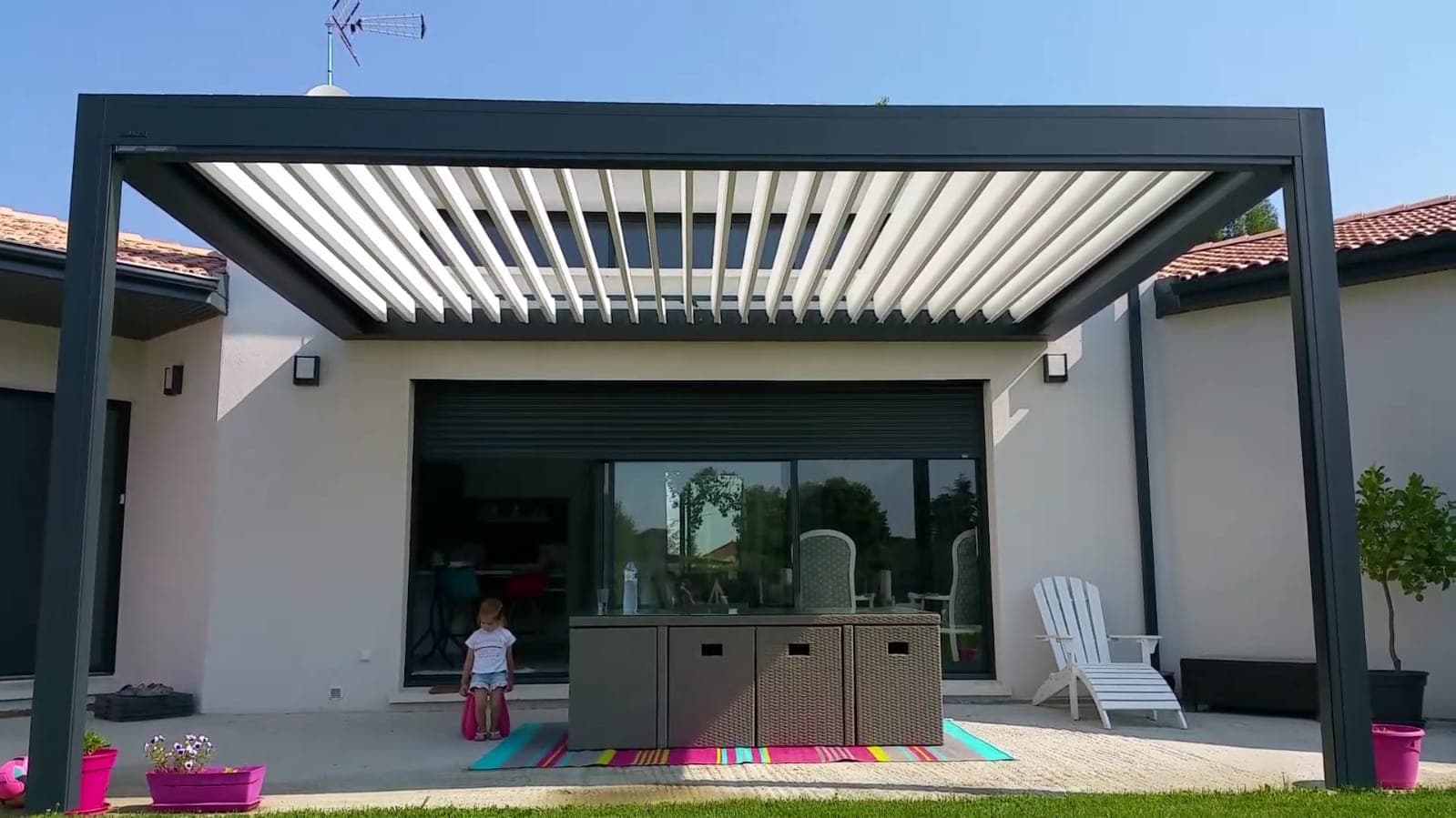 Konut önünde lamelleri açık durumdaki koyu renk pergola