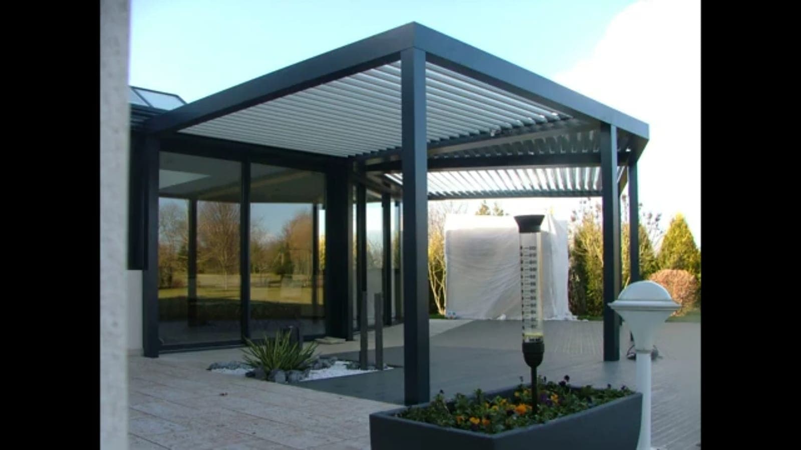 Konut bahçesinde cam panellerle çevrili pergola